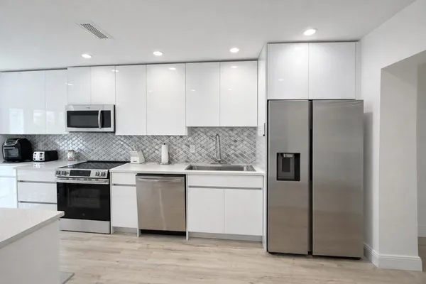 a kitchen with stainless steel appliances granite countertop a refrigerator a stove and a sink