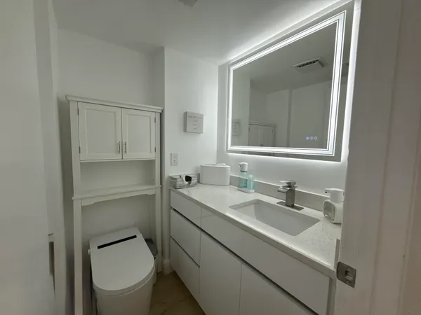 a bathroom with a toilet sink a mirror and vanity