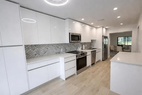 a large kitchen with stainless steel appliances granite countertop a stove a sink and a refrigerator