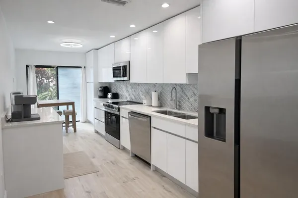 a kitchen with white cabinets and stainless steel appliances