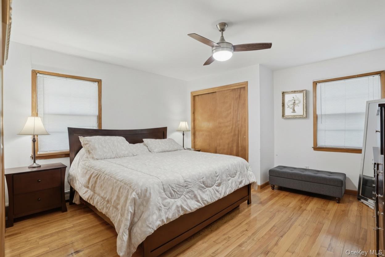 23 Dupay Road Pleasant Valley, NY 12569 - Photo 12 of 24 Bedroom featuring wood-finish flooring, a ceiling fan with integrated lighting, wood-trimmed windows with blinds, and two built-in closet with wood doors