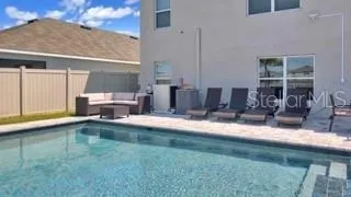 a view of a swimming pool with a patio and a yard