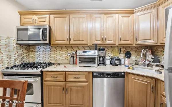 a kitchen with stainless steel appliances granite countertop a stove a sink and a microwave
