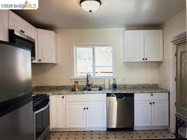 a kitchen with granite countertop white cabinets and stainless steel appliances