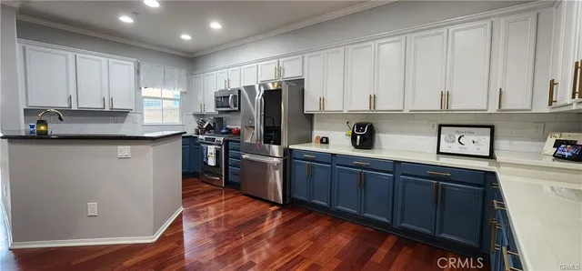 a kitchen with stainless steel appliances granite countertop a refrigerator a sink dishwasher and white cabinets with wooden floor