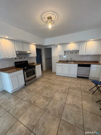 a large kitchen with kitchen island granite countertop a stove a sink a counter space and cabinets