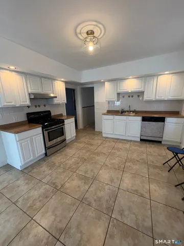a large kitchen with kitchen island granite countertop a stove a sink a counter space and cabinets