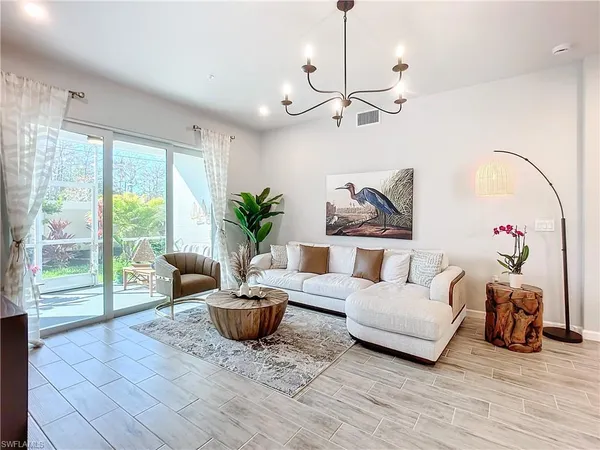 a living room with furniture floor to ceiling window and a potted plant
