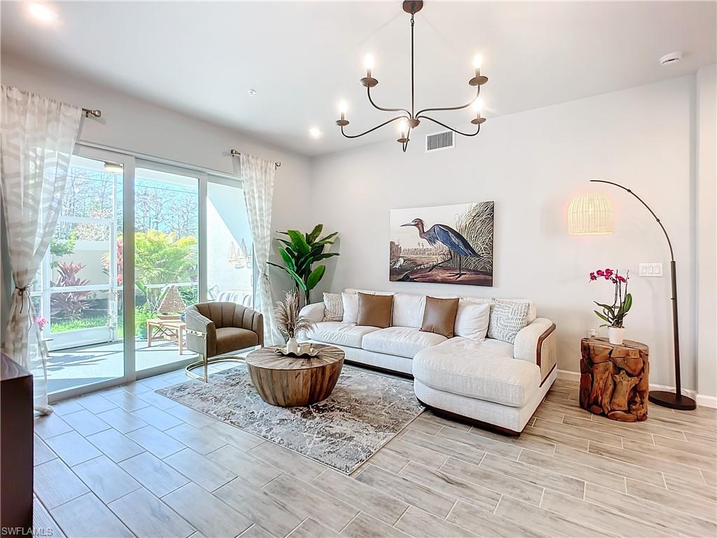 4664 Arboretum Circle, Unit 101 Naples, FL 34112 - Photo 15 of 48 a living room with furniture floor to ceiling window and a potted plant