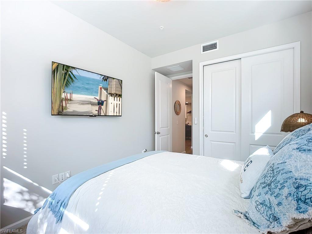 4664 Arboretum Circle, Unit 101 Naples, FL 34112 - Photo 18 of 48 a bedroom with a large bed and a painting on the wall