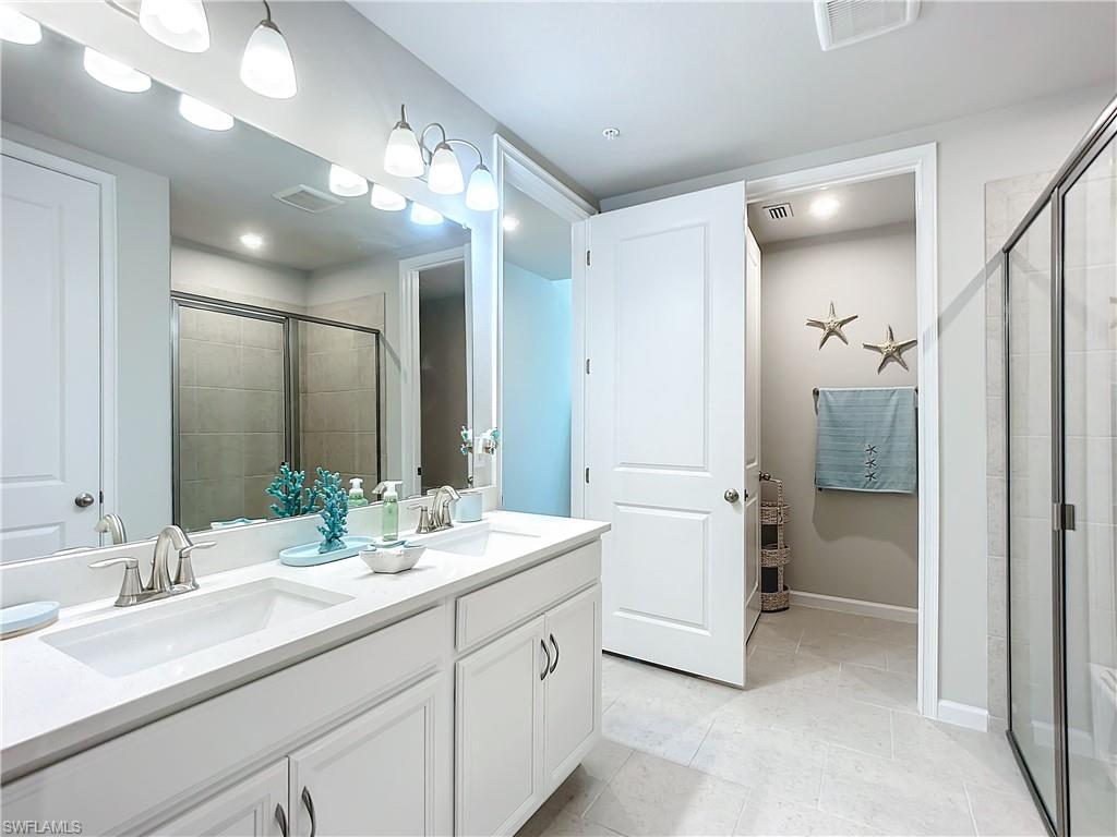 4664 Arboretum Circle, Unit 101 Naples, FL 34112 - Photo 32 of 48 a bathroom with a double vanity sink mirror and shower