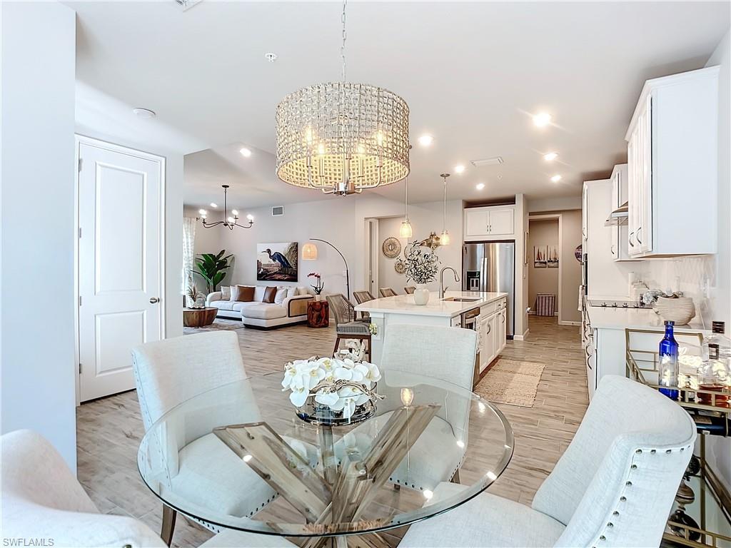 4664 Arboretum Circle, Unit 101 Naples, FL 34112 - Photo 8 of 48 a living room with furniture kitchen and a chandelier