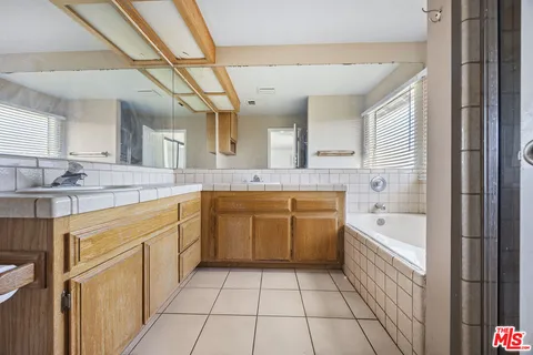 a spacious bathroom with a granite countertop sink mirror and bathtub