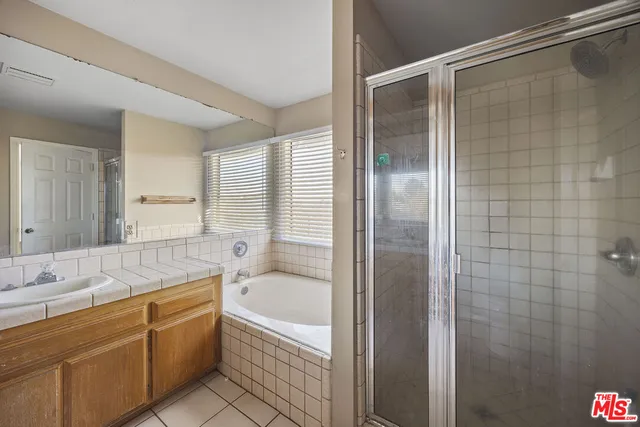 a bathroom with a granite countertop bathtub shower sink vanity and toilet