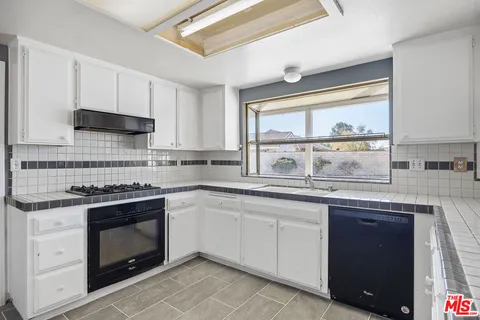 a kitchen with granite countertop white cabinets and appliances