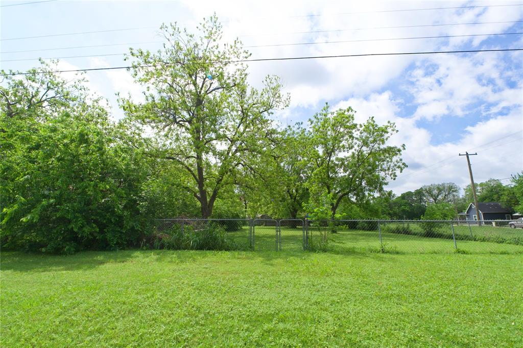 714 Potter Street Gainesville, TX 76240 - Photo 1 of 12 Expansive yard featuring a well-maintained lawn, mature trees, and chain-link fencing