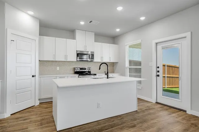 a kitchen with kitchen island a sink stainless steel appliances and cabinets
