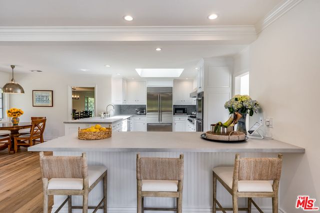 a large kitchen with stainless steel appliances granite countertop a stove and a wooden floors