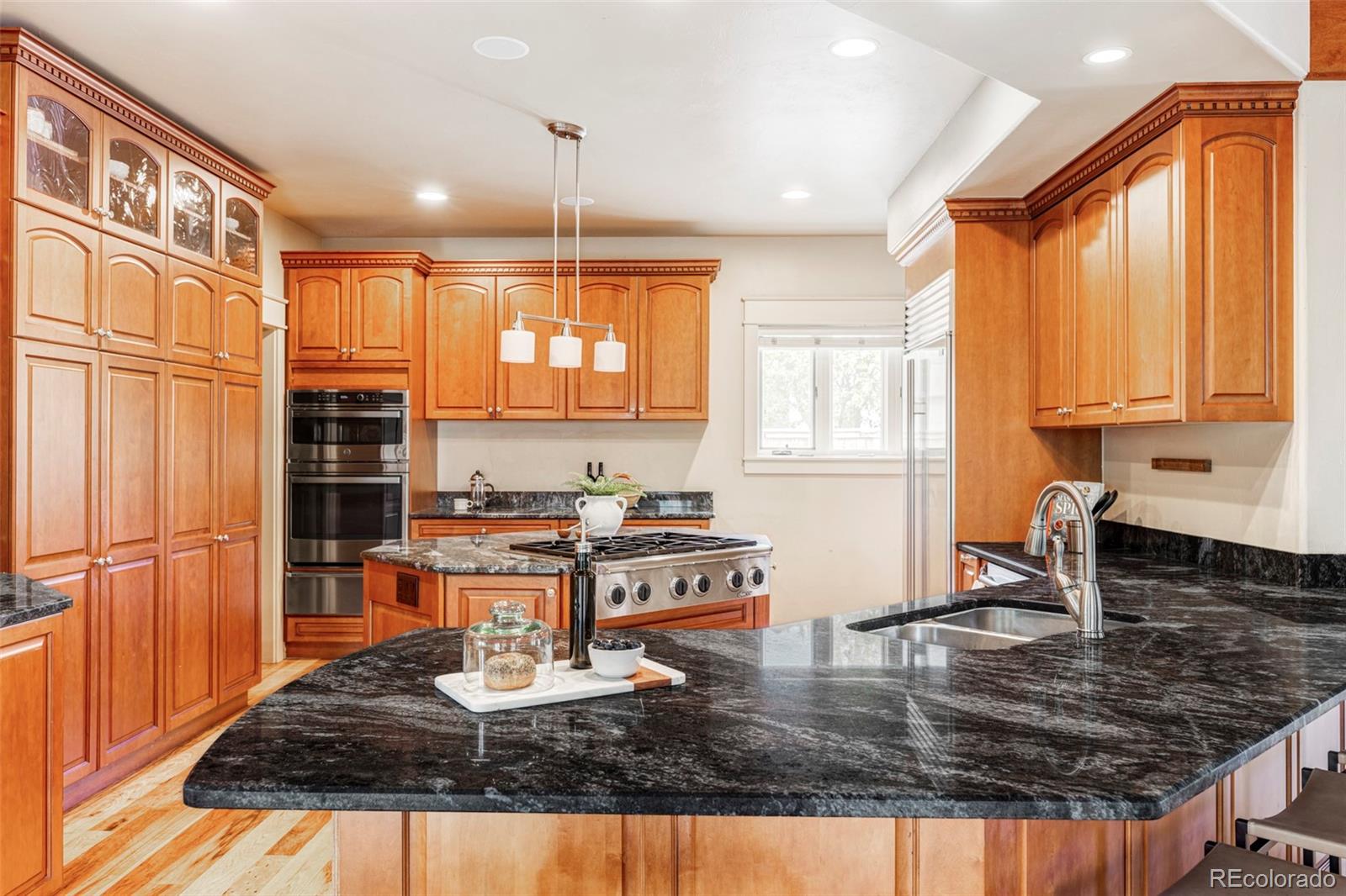 701 Leyden Street Denver, CO 80220 - Photo 16 of 42 a kitchen with kitchen island granite countertop a sink appliances cabinets and a counter top space