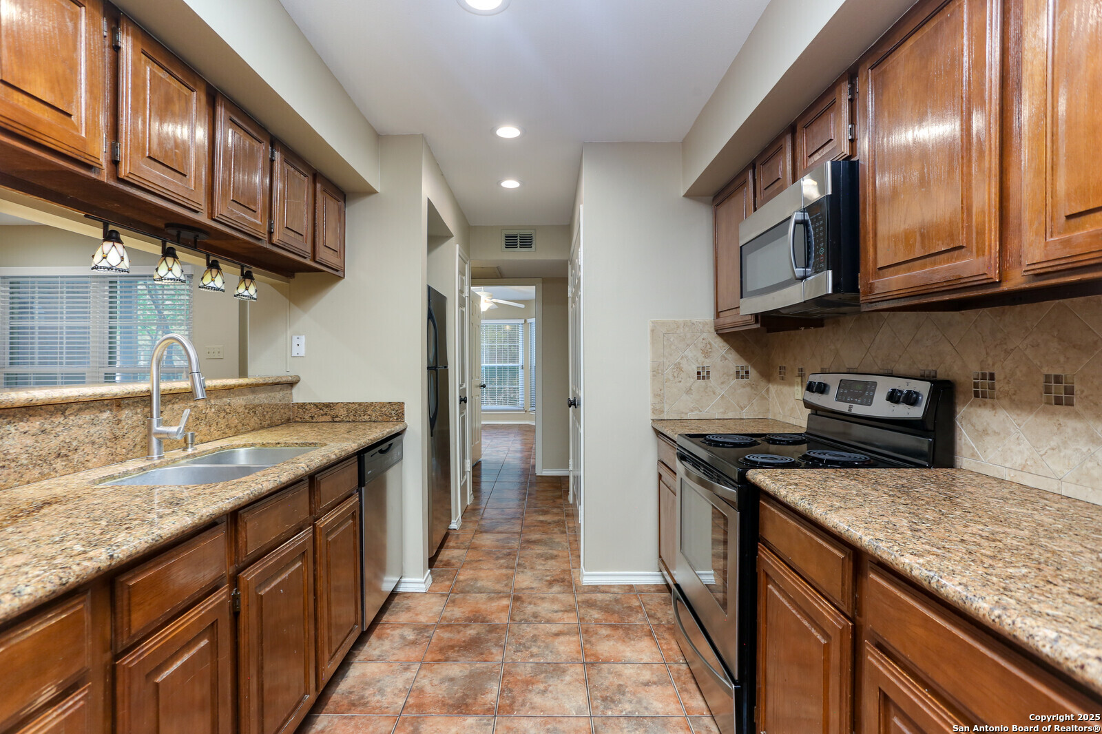 a kitchen with stainless steel appliances granite countertop a sink a stove and a wooden cabinets