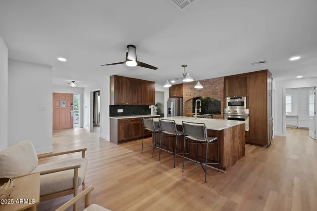 a large living room with stainless steel appliances kitchen island granite countertop a large counter top and chairs