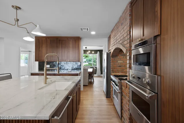 a kitchen with stainless steel appliances granite countertop a sink a stove and a refrigerator