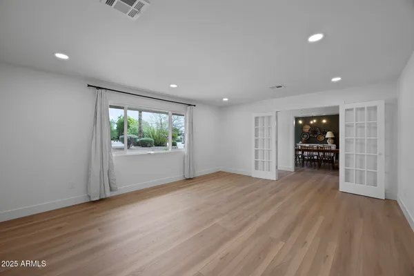 a view of an empty room with wooden floor and windows