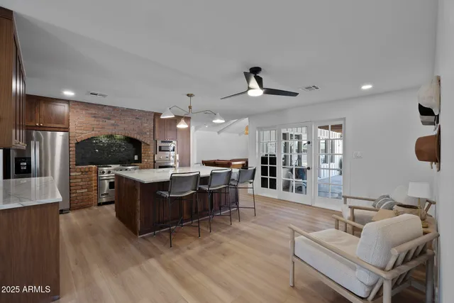 a living room with furniture kitchen view and a wooden floor