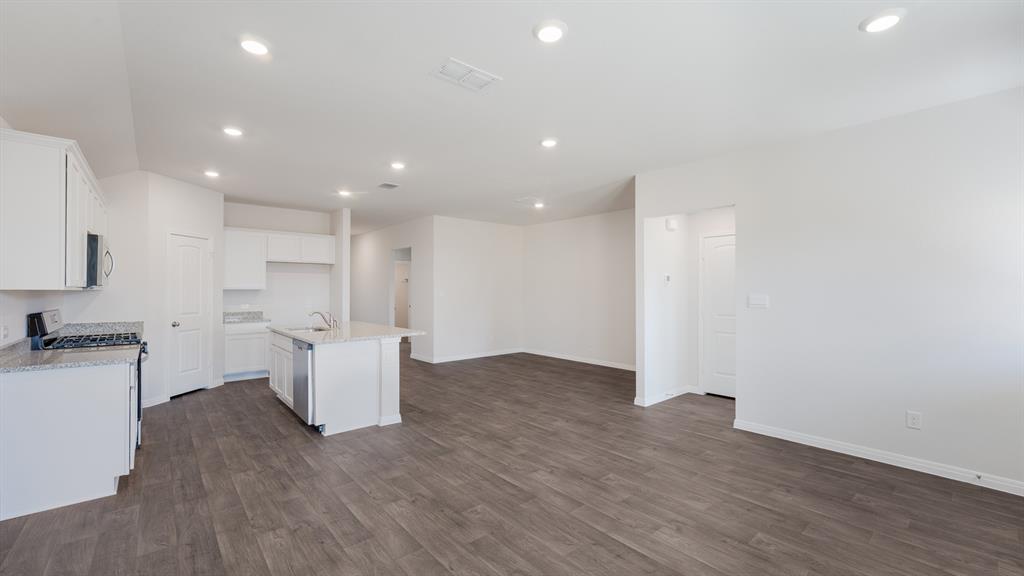 14021 Feinstein Street Manor, TX 78653 - Photo 11 of 25 A pristine open-concept living space features a functional kitchen island and resilient wood-look flooring.