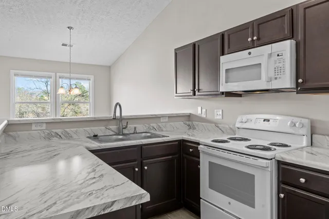 a kitchen with stainless steel appliances granite countertop a sink stove a microwave and cabinets