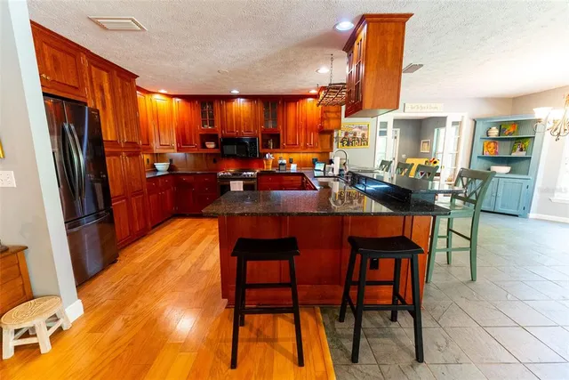 a kitchen with granite countertop a refrigerator stove and sink