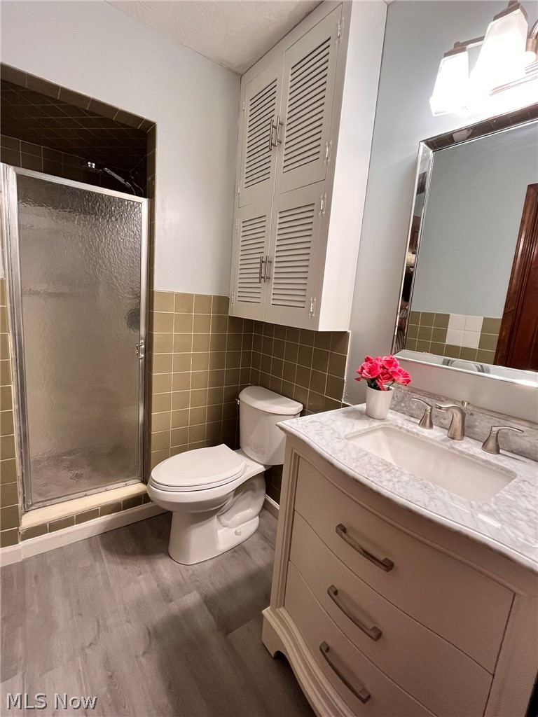 2752 Copley Road Akron, OH 44321 - Photo 22 of 35 Bathroom with vanity, a shower stall, light wood-type flooring, tile walls, and wainscoting