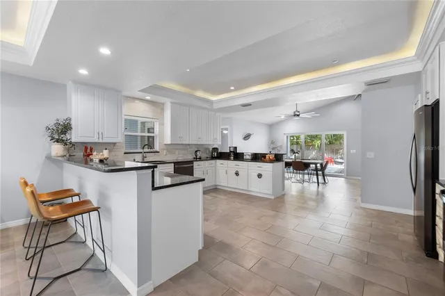 a kitchen with stainless steel appliances a refrigerator a stove a sink dishwasher and a dining table with wooden floor