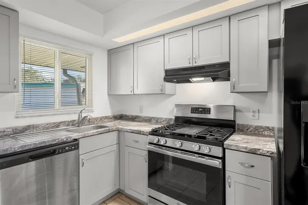 a kitchen with granite countertop white cabinets and white appliances
