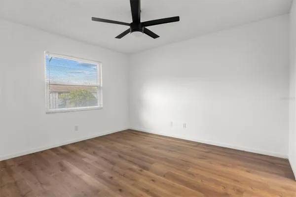 an empty room with a window and a ceiling fan