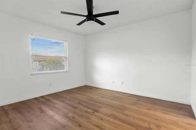 an empty room with a window and a ceiling fan