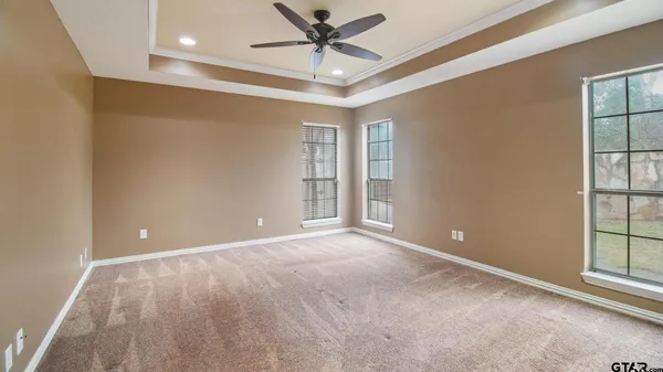 an empty room with windows and fan