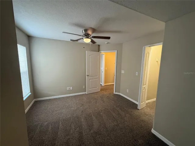 a view of a big room with a chandelier fan and windows