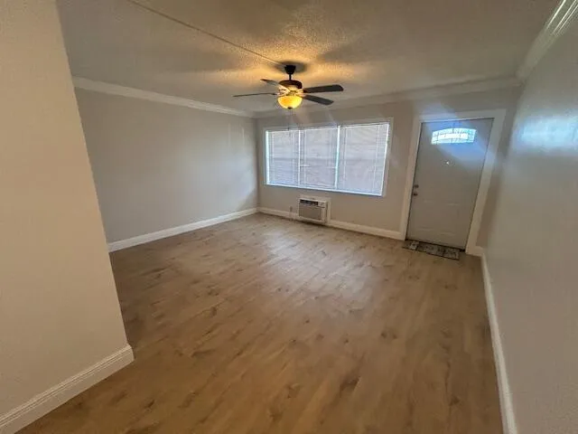 an empty room with chandelier fan and windows