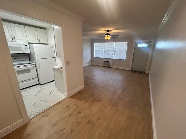 an empty room with wooden floor cabinet and windows