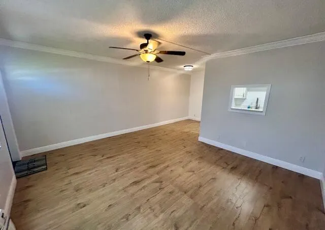 an empty room with wooden floor chandelier fan and windows