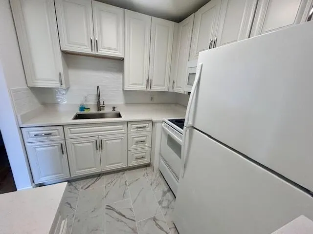 a kitchen with white cabinets and white appliances