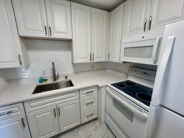 a kitchen with white cabinets and white appliances