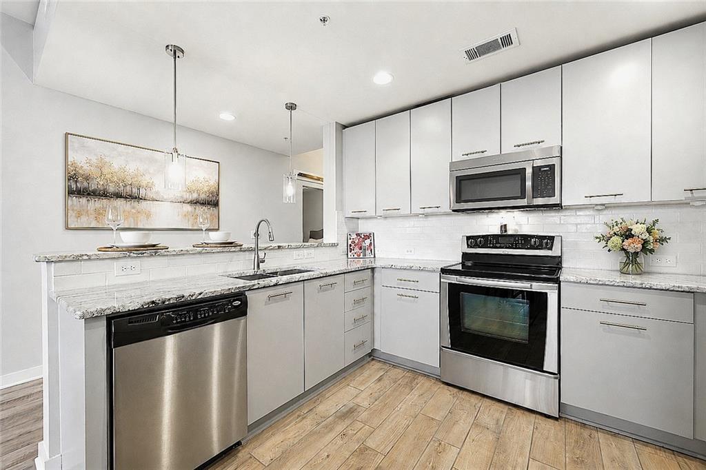 3300 Windy Ridge Parkway Southeast, Unit 1112 Atlanta, GA 30339 - Photo 6 of 43 a kitchen with granite countertop white cabinets sink and stainless steel appliances