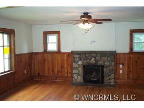 3790 Pigeon Road Waynesville, NC 28786 - Photo 8 of 24 a living room with a fireplace furniture a ceiling fan and a window