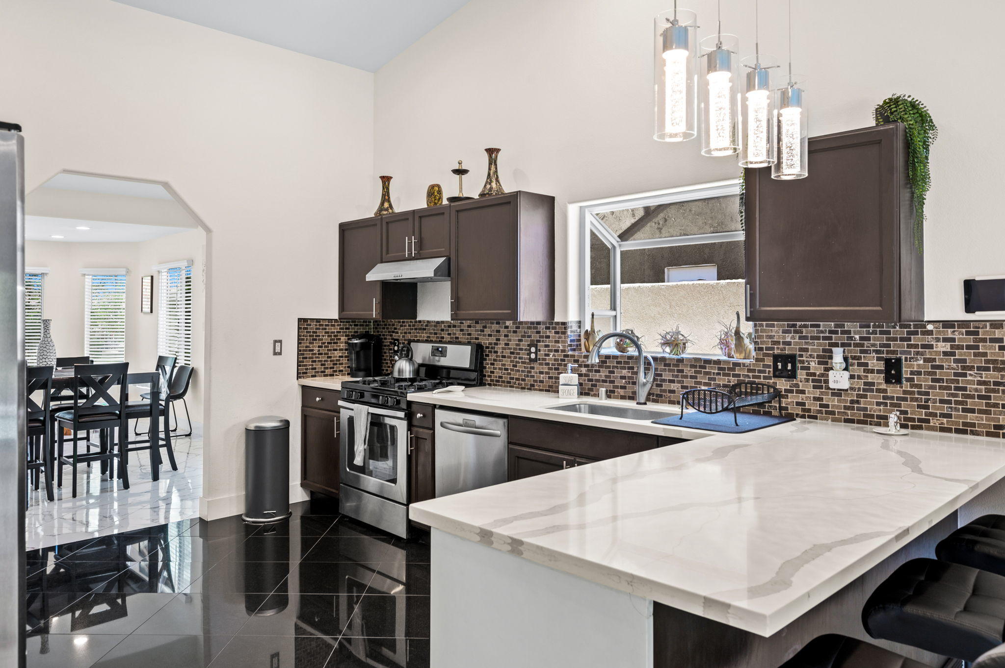 68210 Empalmo Road Cathedral City, CA 92234 - Photo 13 of 34 a kitchen with stainless steel appliances kitchen island granite countertop a table chairs and a refrigerator