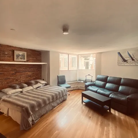a bedroom with a bed couch and a dresser next to a window