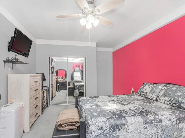 a bedroom with a bed and a flat tv screen on dresser
