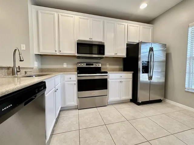 a kitchen with stainless steel appliances granite countertop a stove a sink and a refrigerator