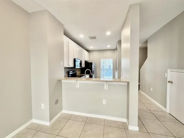 a kitchen with granite countertop white cabinets a refrigerator and a sink